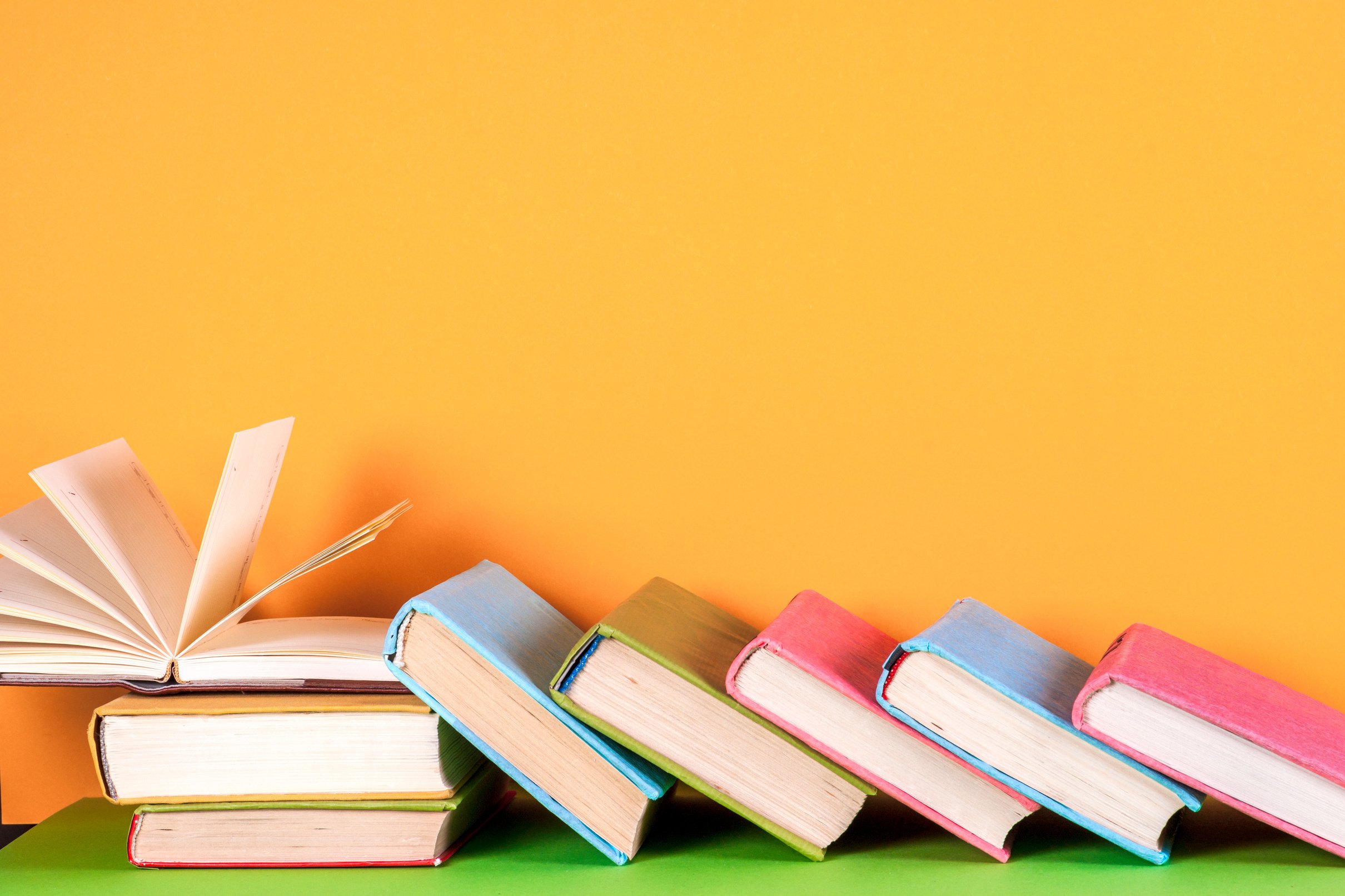 Open book, hardback books on bright colorful background.